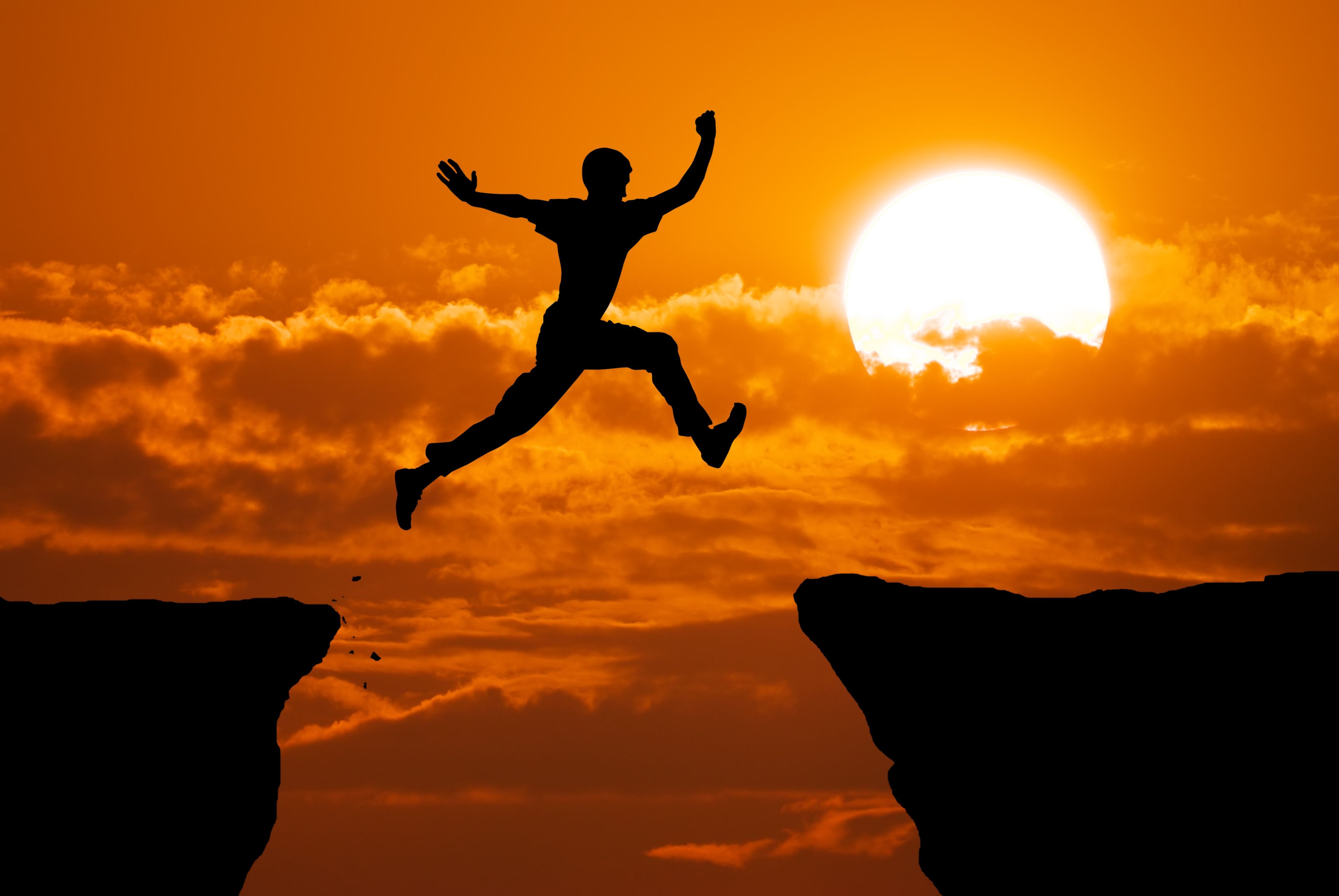 Man jumping from cliff edge to another