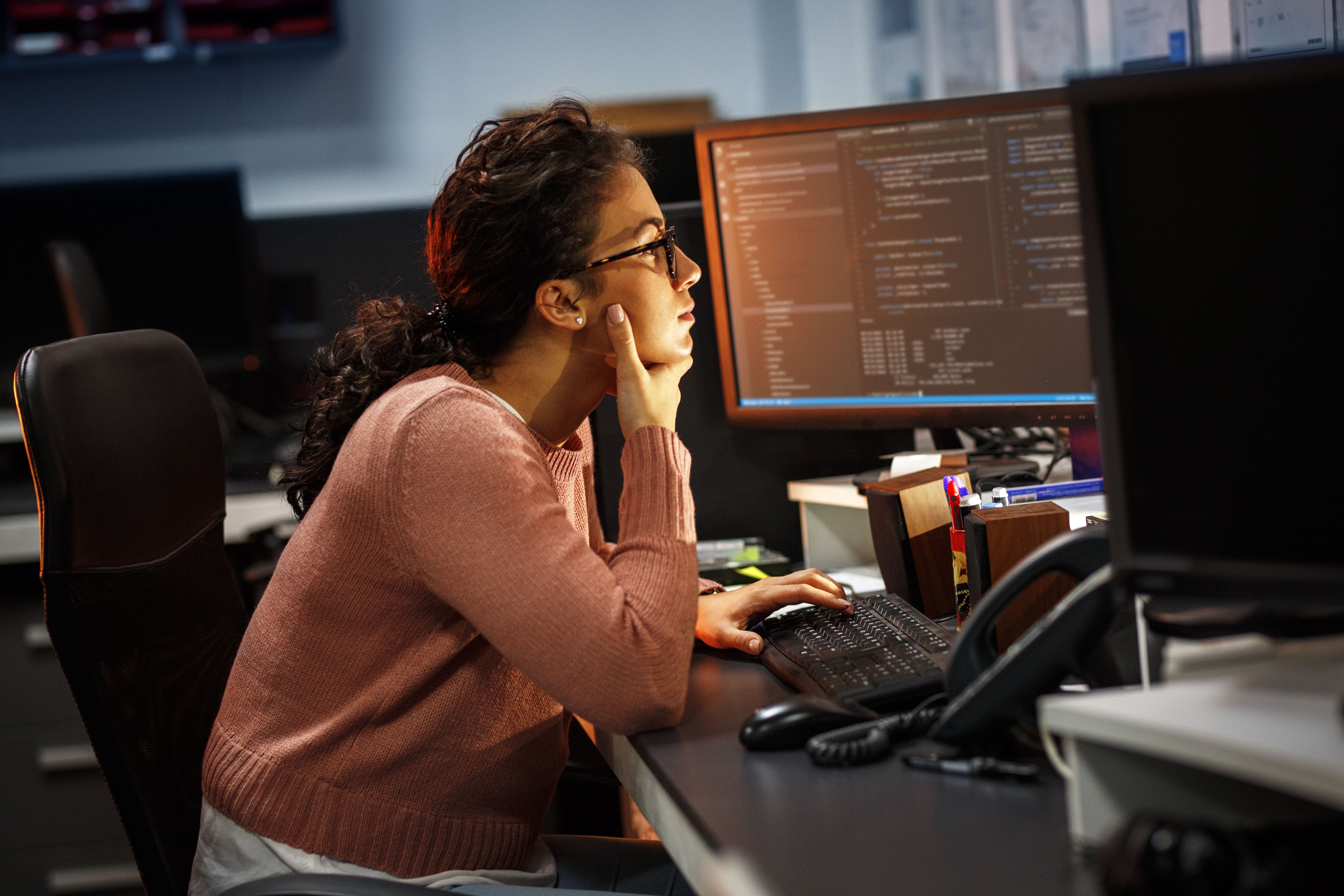 Woman typing and looking at several computer screens