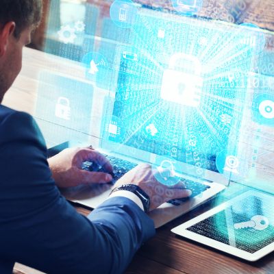 Man typing on a laptop displaying a padlock icon and digital back representing cyber security